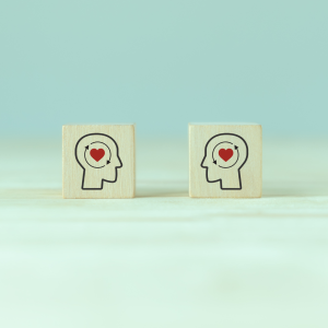 Two blocks of woods with the shape of heads with hearts withing representing empathy in therapy