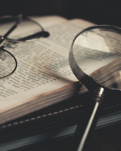 An open book with a magnifying glass and glasses